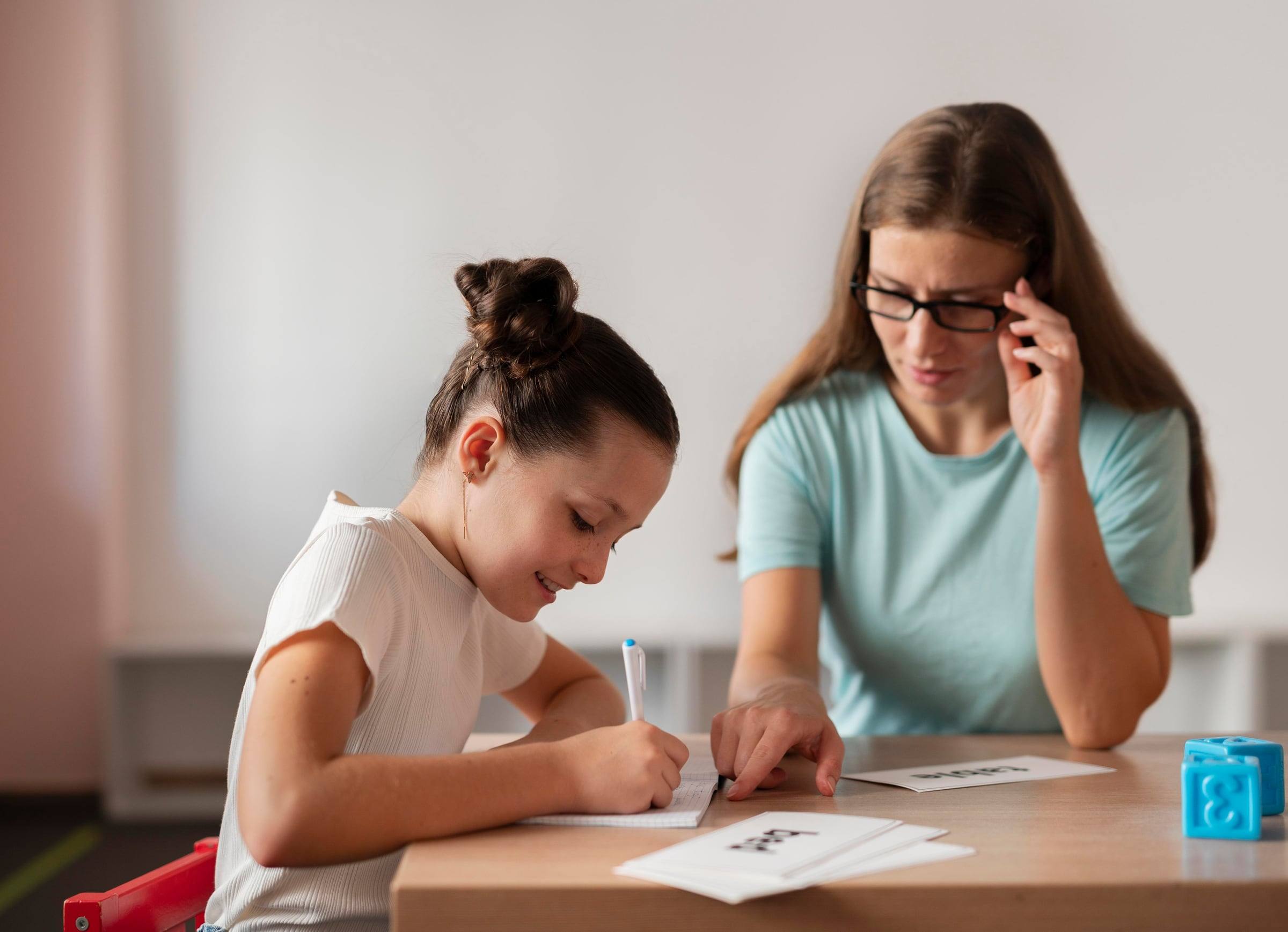 Niña escribiendo junto a su terapeuta